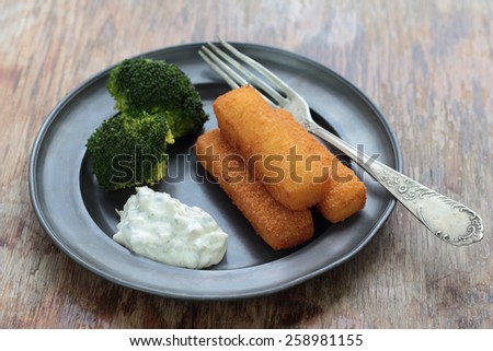 Fried fish fingers with broccoli and tartar sauce.