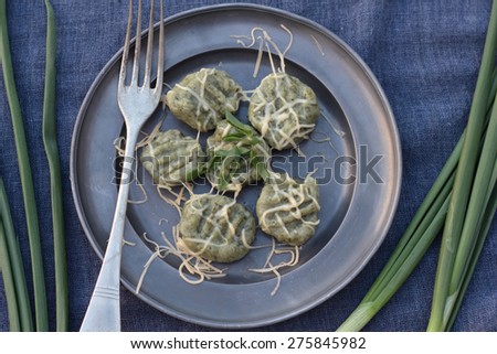 Gnocchi with spinach and grated cheese on a tin plate.