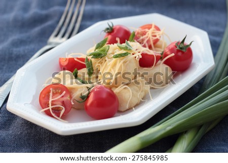 Gnocchi with tomatoes and grated cheese on a blue plate.