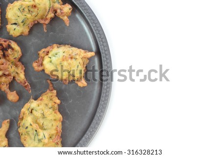 Deep fried courgette cakes, served on a tin plate.