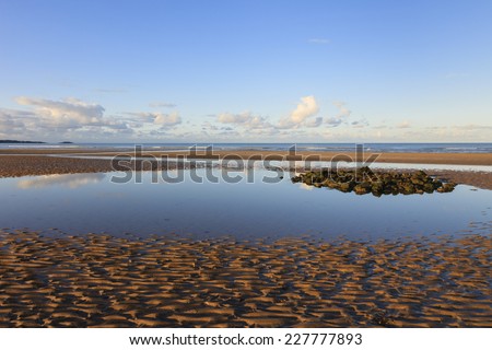 Tidal pool on Traeth Coch empty sandy beach at low tide in Red Wharf Bay, Isle of Anglesey, North Wales, United Kingdom, Great Britain, Europe.