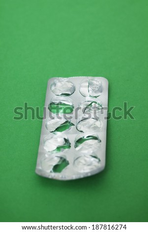 Pill packet already opened, on green background