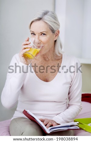 Senior woman drinking an orange juice.