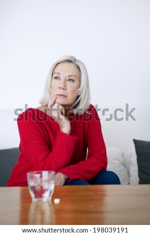 Senior woman hesitating to take a medicine.