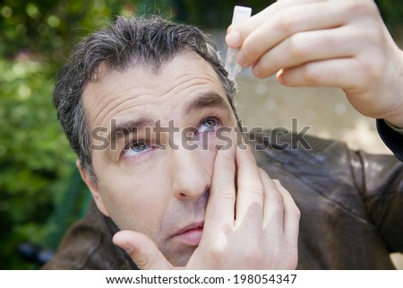 Man using eye lotion