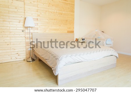 Bedroom in soft beige colors with blue decoration. Over the bed was a large frame with a white background where can be your tex.