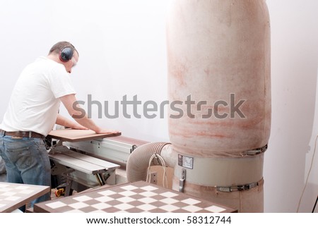 Carpenter working on an electric buzz saw cutting some boards