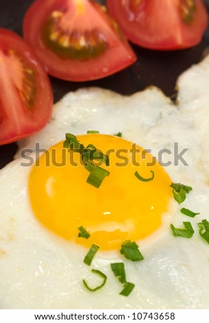 Egg sunny side up garnished with chives and cherry tomatoes