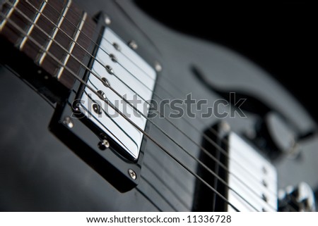 Detail of an electric guitar showing part of a fretboard and chrome pickups