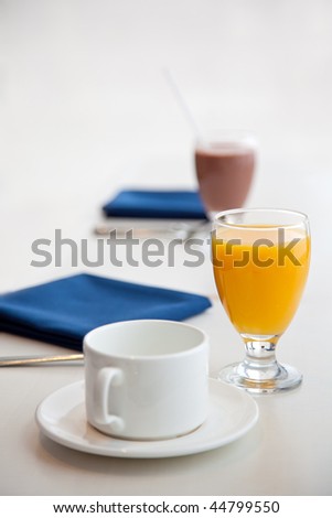 Waiting for healthy breakfast, table with orange juice, chocolate milk, and an empty cup for coffee or tea