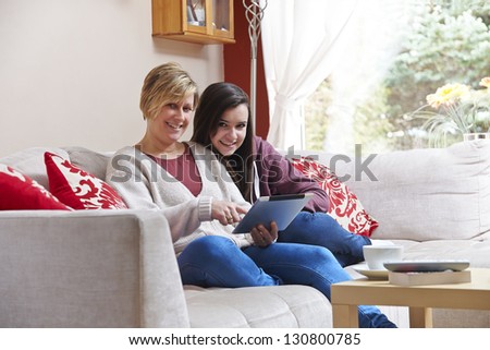 Mother and daughter using tablet pc while relaxing at home