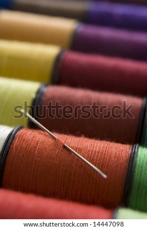 various colours of cotton reels in a row with a needle