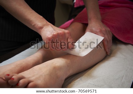 beautician applying wax to females leg to remove hair