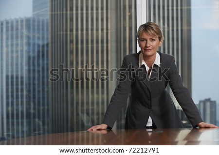 Business woman leaning on chair in boardroom looking at camera