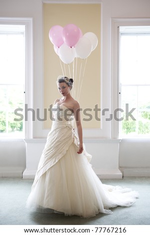 stock photo pretty bride in her wedding dress holding balloons in front of 