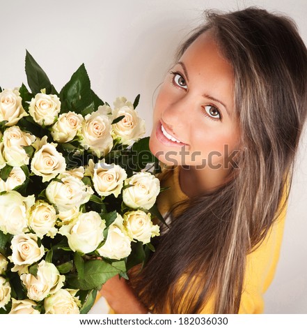 Portrait of attractive caucasian woman brunette with beautiful bouquet of roses in her arms.