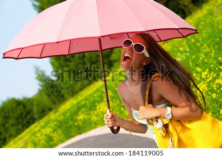 Happy young woman under pink umbrella in summer day (face in the shade of umbrella). Girl looking up at sky smiling cheerful.
