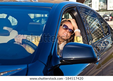 Beautiful young woman driving her luxury car. Attractive woman sitting in car driver seat.