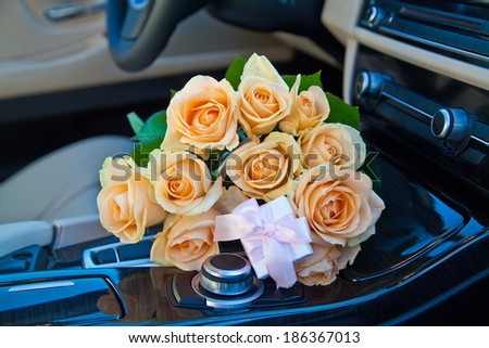 Bouquet of yellow roses with present in luxury car.