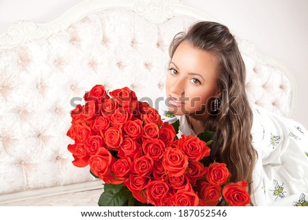 portrait of attractive caucasian smiling woman with a large bouquet of coral roses in her arms