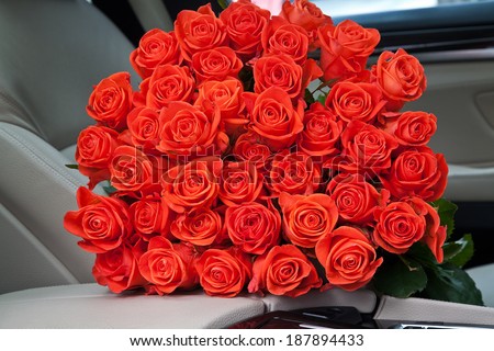 bouquet of beautiful red roses in luxury car. Composition for a romance or anniversary.