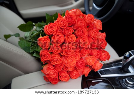 bouquet of beautiful red roses in luxury car. Composition for a romance or anniversary
