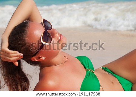Fashion girl in beautiful green bikini lying on caribbean beach. Vacations And Tourism Concept. Tropical Resort.