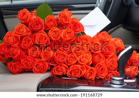 bouquet of beautiful red roses in luxury car. Composition for a romance or anniversary