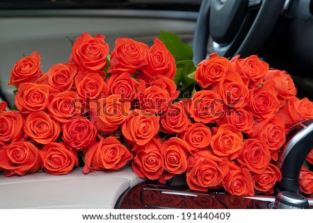Bouquet of beautiful red roses in luxury car. Composition for a romance or anniversary.