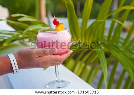 Cocktail in human hand. Man Relaxing with Tropical Drink.