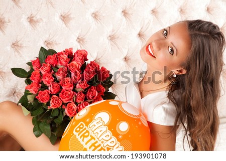Portrait of attractive brunette smiling woman with a large bouquet of pink roses in her arms. Holidays and celebrations concepts.
