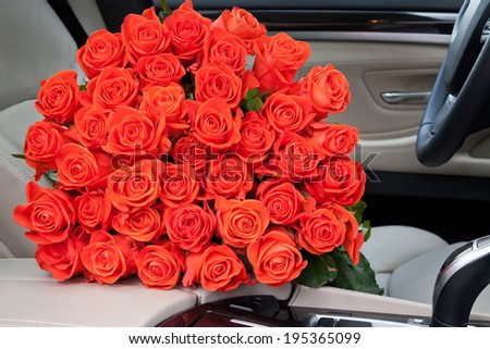 Big bouquet of beautiful red roses in luxury car. Composition for a romance or anniversary