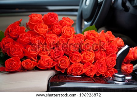 Big bouquet of beautiful red roses in luxury car. Composition for a romance or anniversary