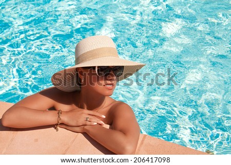 Beautiful woman in straw hat posing by the pool, summer day, outdoor