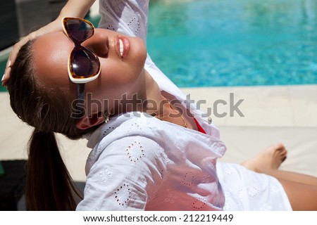 Portrait of sexy woman, relaxing at the luxury poolside. Girl at travel spa resort pool. Summer luxury vacation. (focus on woman face)