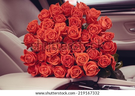 Bouquet of red roses in luxury car. Composition for a romance or anniversary.