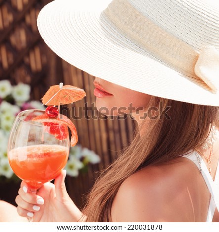 woman in white hat relaxing with fresh juice. Summer vacation. (focus on face)