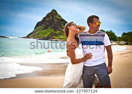 Honeymoon couple romantic in love hugging at tropical beach, Hawaii islands. Travel holidays vacation getaway.
