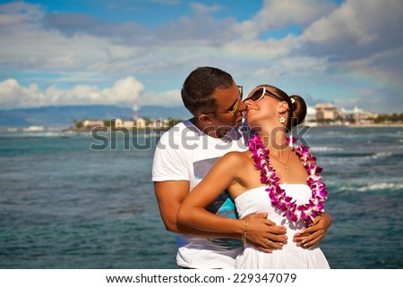 Romantic happy couple on the Hawaiian beach after rain, rainbow in the sky. Summer holidays, love, travel, relationships - concept