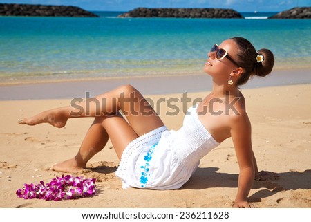 Young beautiful female enjoying sunny day on tropical beach. Summer luxury vacation in Hawaii.