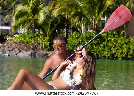 Romantic honeymoon couple swimming in surfboard, tropical summer holiday vacation in Hawaii. Carefree stress free lifestyle concept.