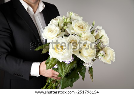 well-dressed man holding a bouquet of flowers, white roses. Holidays and celebrations. Wedding day.