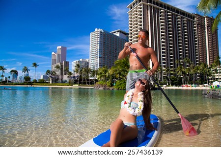 Romantic honeymoon couple swimming in surfboard, tropical summer holiday vacation. Hawaiian beach vacation. Summer in Waikiki beach, Honolulu city, Oahu, Hawaii, USA.