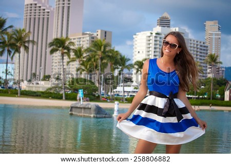 Happy beautiful woman in blue summer dress walking in Waikiki beach, Honolulu, Oahu on exotic holidays. Girl on vacation smiling happy.