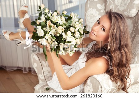 A young woman holding a bunch of roses. Glamour portrait of beautiful girl with fresh daily makeup and romantic wavy hairstyle. Beauty model woman face.