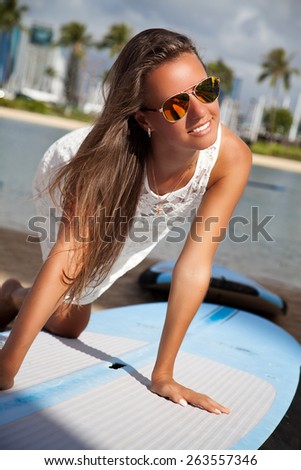 Beach woman at surfboard rental surf shop. Happy girl trying surf board on famous Waikiki beach, Honolulu City, Oahu, Hawaii, USA.