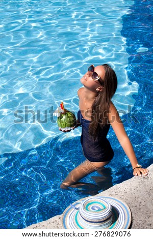 Sexy cheerful woman in bikini relaxing at the luxury poolside. Girl at travel spa resort pool. Summer luxury vacation.