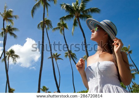 Hawaii travel vacation, beautiful young woman taking in the sun at the beach in Hawaii. Young adult on Waikiki beach, Honolulu, USA. Girl enjoying sunlight, on luxury spa resort.