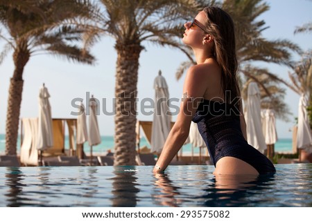 Beautiful woman in the pool at a holiday resort. Portrait of happy young female enjoying in the swimming pool.