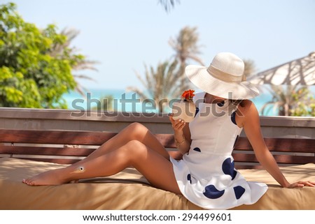 Young woman in white dress with gold tattoo on the leg relaxing at the luxury resort. Girl at travel spa resort. Summer luxury vacation. UAE